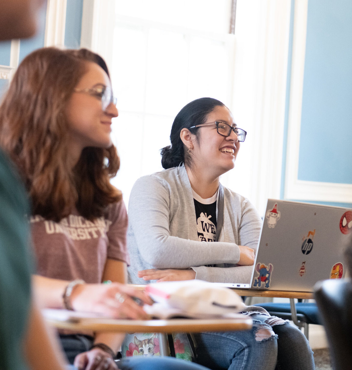 Two female students smile during class.